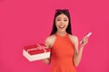 Image of excited surprised young asian woman standing isolated over pink wall background holding gift box using mobile phone Royalty Free Stock Photo