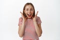 Image of excited and surprised young woman rejoice over big surprise, hold hands near face, shouting and smiling amazed Royalty Free Stock Photo