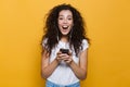 Image of excited woman 20s with curly hair holding smartphone an Royalty Free Stock Photo