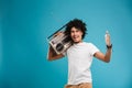 Excited young african curly man holding boombox.