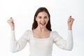 Image of excited young lady standing isolated over white background make winner gesture. Girl winning and rejoicing Royalty Free Stock Photo