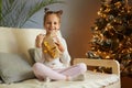 Image of extremely happy little girl with funny hair buns holding wrapped present box, looking at camera with toothy smile, Royalty Free Stock Photo