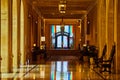 Fancy doorway framed by pride flags at end of golden reflective hallway