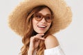 Image of fashion cute woman 20s wearing big straw hat and sunglasses posing on camera with happy smile, isolated over white Royalty Free Stock Photo
