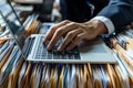Businessman typing on laptop surrounded by stacked files and documents