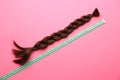Braided strand and measuring tape on color background. Concept of hair donation