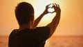 Silhouette of a Man Making Heart Shape with Hands at Sunset Royalty Free Stock Photo
