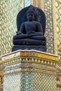 The image features a meditative Buddha statue in a temple. The black statue, sitting on a pedestal, is set against a vibrant