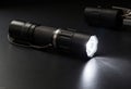 A sleek black flashlight illuminating a dark surface with bright light Royalty Free Stock Photo