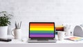 A modern home office setup with laptop and a rainbow flag on screen, for pride day. Generative AI. Royalty Free Stock Photo