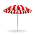 A vibrant red and white striped beach umbrella providing shade on a sunny day Royalty Free Stock Photo