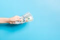 Image of female hand holding a bundle of dollars on blue background. Payment concept Royalty Free Stock Photo