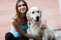 Image of fitness brunette hugging labrador near building wall