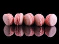 five different types of pink candy macarons on a reflective surface