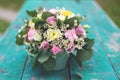 Image of cute flowers arrangement with white eustoma, spray roses, carnations in the mint tea cup on the wooden table Royalty Free Stock Photo