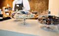 Image focused on cloche with pastries and chocolate cheese creamy desserts on a restaurant countertop with blurred chef in white