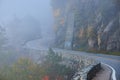 Foggy road with stone wall winding along cliffs into foggy morning Royalty Free Stock Photo