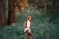 Image of a forest hunter, an attractive girl with long red hair in a white shirt and leather pants goes hunting, holds a Royalty Free Stock Photo
