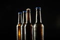 Image of four beer bottles one open the rest with blue crown caps, with copy space on black
