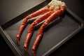 Image of fresh crab phalanges on oven-tray over dark background with copyspace