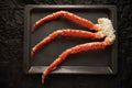 Image of fresh crab phalanges on oven-tray over dark background with copyspace