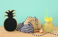 Image of fresh lemonade drink in cute pineapple shape glass with twisted straw next to bikini swimsuit and beach fedora hat over w Royalty Free Stock Photo