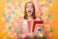 Image of funny crazy young adult woman holding papers, standing plastered with stickers and screaming loudly, posing against Royalty Free Stock Photo