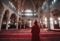 Middle age woman in red clothes prays in sancaklar camii (mosque)