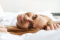 Image of ginger happy woman smiling at camera while lying in bed