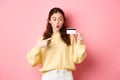 Image of glamour girl going shopping, looking excited and pointing at plastic credit card, standing against pink Royalty Free Stock Photo