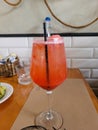 Image of a glass of aperol spritz cocktail on a wooden table in a restaurant