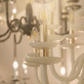 Image of a glowing chandelier with white glass fittings and candlelight shades on a gold stand Royalty Free Stock Photo