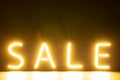 Image of glowing neon sale text over orange background