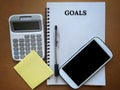 Image with goals text on a notepad with stationery and smart phone background.