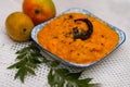 Image of a Goan/konkan mango curry dish made of ripe mangoes on a plate surrounded by mango fruits-perfect for cafe menu