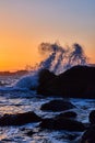 Golden hour on ocean with large wave crashing over rocks Royalty Free Stock Photo