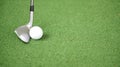 Image of golf iron or club and golf ball on green grass