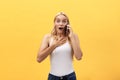 Image of gorgeous woman in casual being surprised or excited to receive pleasant talk on her cell phone, over yellow