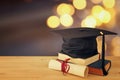 Image of graduation black hat over old books next to graduation on wooden desk. Education and back to school concept Royalty Free Stock Photo