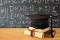 Image of graduation black hat over old books next to graduation on wooden desk. Education and back to school concept. Royalty Free Stock Photo