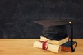 Image of graduation black hat over old books next to graduation on wooden desk. Education and back to school concept Royalty Free Stock Photo