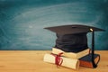 Image of graduation black hat over old books next to graduation on wooden desk. Education and back to school concept. Royalty Free Stock Photo