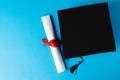 Image of graduation hat and diploma on blue surface Royalty Free Stock Photo