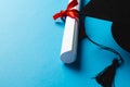 Image of graduation hat and diploma on blue surface Royalty Free Stock Photo