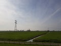 Meadow with brook and high voltage power lines Royalty Free Stock Photo