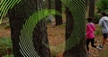 Image of green line spiral rotating over woman and man running in forest