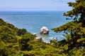 Greenery framing giant white rock sticking out of shallow bay waters with distant deeper blue water Royalty Free Stock Photo