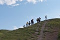 Image of group of tourists hikers walking up the steep hill with view of blue sky in the background