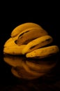 A hand of bananas on a wooden table and dark background Royalty Free Stock Photo