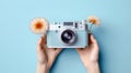 Image of hand with camera and flowers on empty blue background Royalty Free Stock Photo